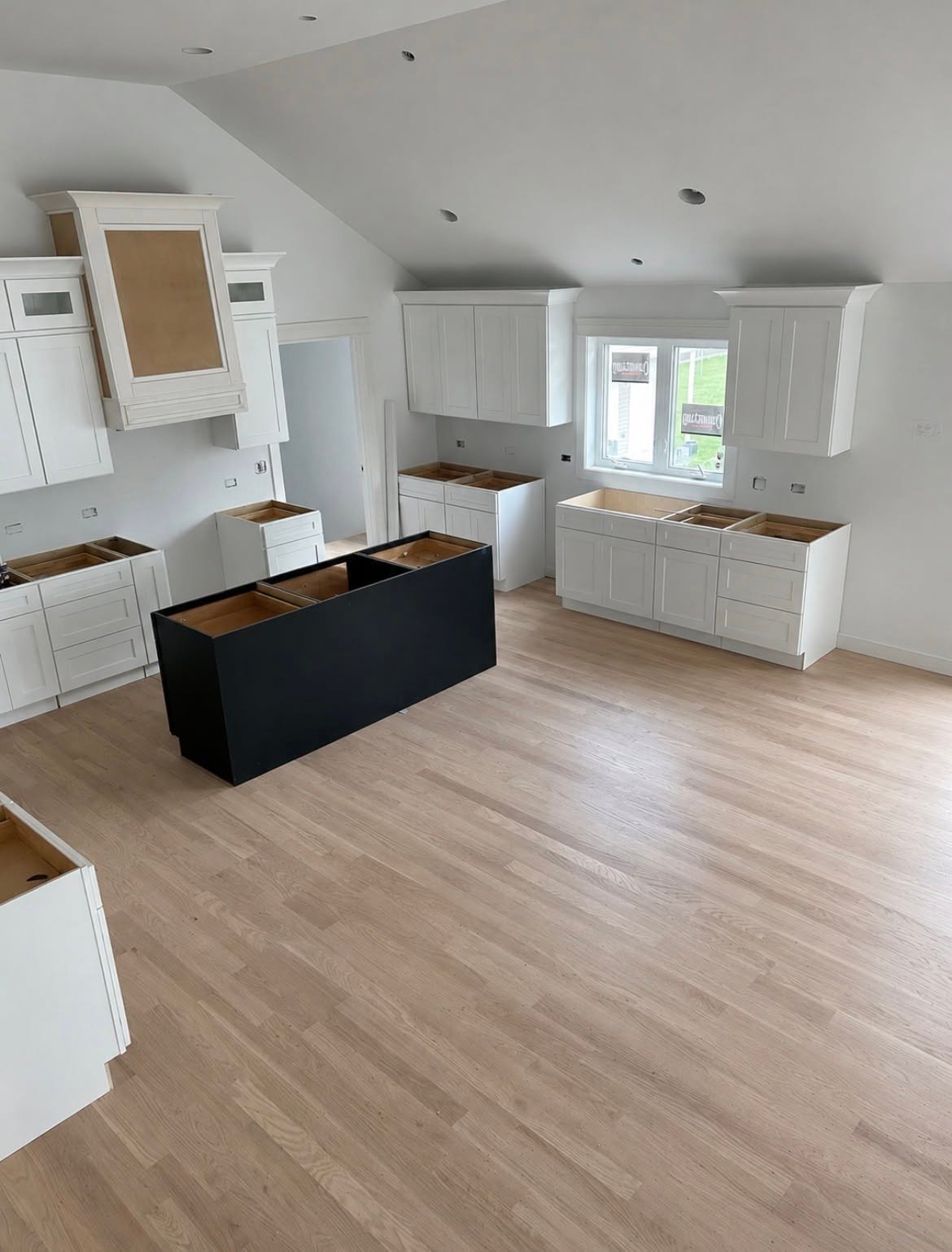 Wide-plank hardwood flooring installed through a kitchen with island